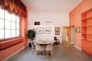 Une pièce avec une table ronde, des chaises, une plante en pot et des œuvres d’art accrochées aux murs.