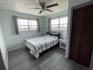 A bedroom with a bed, a nightstand, a ceiling fan, and a window.