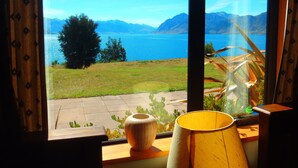 Ein Zimmer mit einem großen Fenster und Blick auf einen See und Berge.