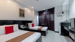 A modern hotel room with two beds, a desk, a chair, and a television. - Check Inn Pension Arcade (Dumaguete)