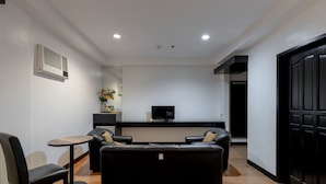A modern living room with a sofa set, a small table, a TV, and a decorative vase. - Check Inn Pension Arcade (Dumaguete)