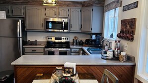 A modern kitchen with grey cabinets, stainless steel appliances, and a wooden island.