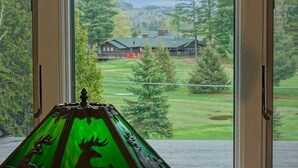 A view through a window with a green decorative object featuring deer silhouettes.