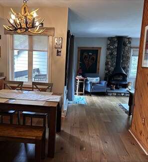 Ein gemütliches Wohnzimmer mit Kamin aus Stein, einer Essecke mit Holztisch und einer Kristallleuchtre.