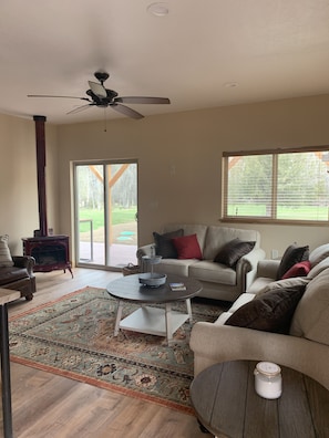 A living room with a fireplace, a ceiling fan, a sofa, a coffee table, and a large window.