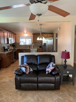 Relax in this stylish living space with a central sofa, side table, and modern kitchen area.