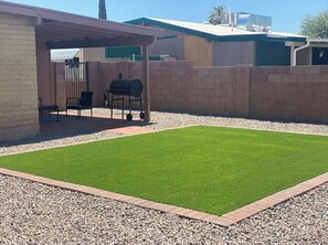 Enjoy outdoor cooking under the covered patio with a barbecue grill and a well-maintained lawn.