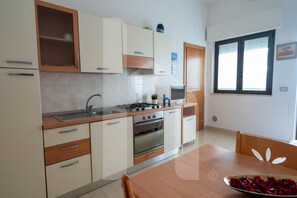 Eine moderne Küche mit Herd, Backofen und Spüle, einem Esstisch mit Stühlen und einem Fenster mit Hinweisschild.