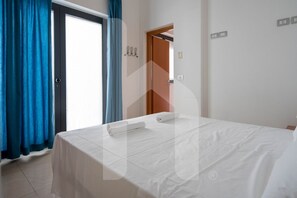 Ein Hotelzimmer mit Bett, Tür und einem Vorhangfenster.