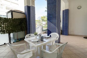 A patio area with a table and chairs, a potted plant, and blue-tiled walls.