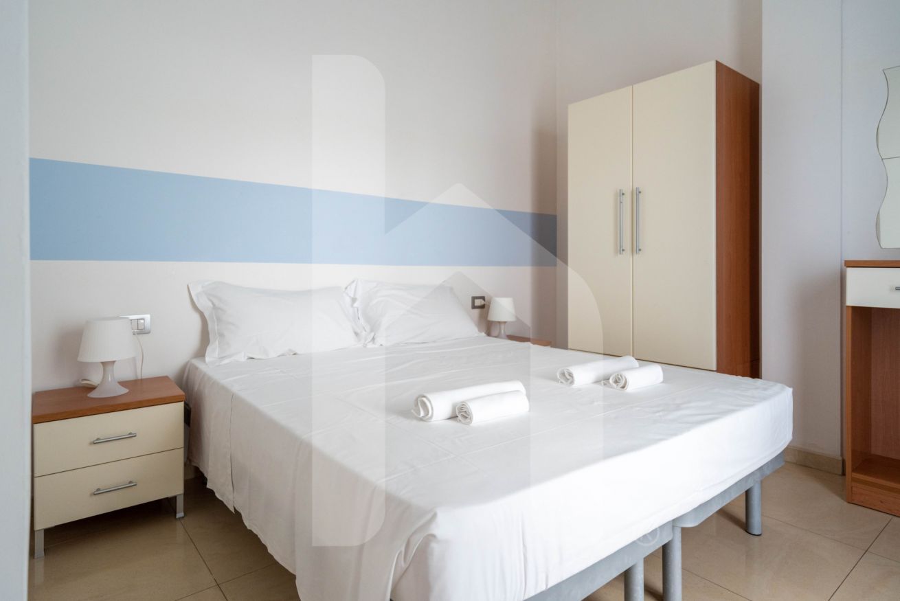 Ein Hotelzimmer mit Bett, Nachttisch, Kleiderschrank und Spiegel.