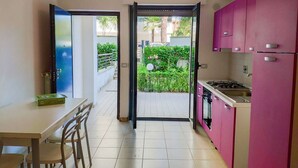 A compact kitchen with pink cabinets, a gas stove, and a dining area with a table and chairs. - Holiday Rendez Vous 4 - Two-room apartment on ground floor with garden (Pineto)