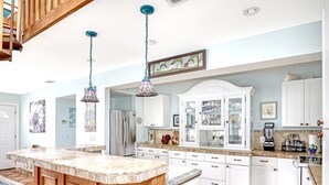 A kitchen with a central island, white cabinets, and a stainless steel refrigerator. - Tropical Chalet w/ 3 King Bedrooms. 3 patios, and an Above-Ground Pool! (Sebastian)