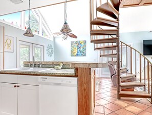 Een moderne keuken met een inbouwvaatwasser, een houten trap en een groot raam.