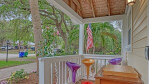 A wooden porch with a railing, a small table, and two purple chairs. - Tropical Chalet w/ 3 King Bedrooms. 3 patios, and an Above-Ground Pool! (Sebastian)
