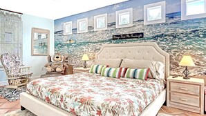 A bedroom with a large bed, two bedside tables, a chair, a teddy bear, and a mural of the ocean. - Tropical Chalet w/ 3 King Bedrooms. 3 patios, and an Above-Ground Pool! (Sebastian)