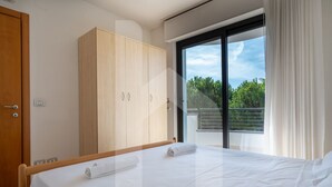 A hotel room with a bed, a wooden wardrobe, a sliding glass door to a balcony, and a view of greenery outside. - Holiday Rendez Vous 38 - Third floor apartment with pool view (Pineto)