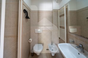 A bathroom with a toilet, bidet, and sink.