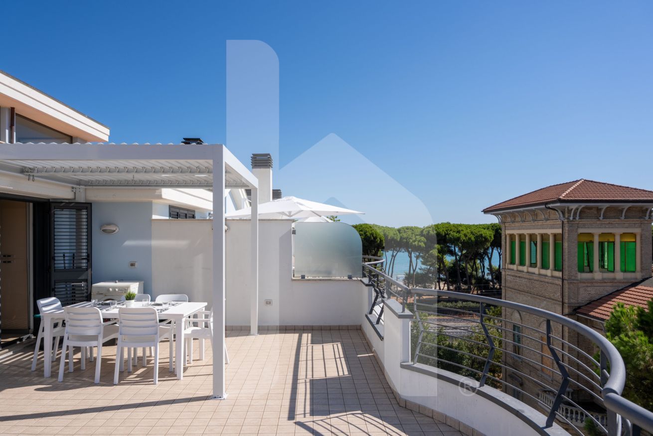 A rooftop terrace with a dining area, a water tank, and a view of the sea.