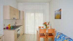 Una cocina compacta con armarios de madera, una mesa de comedor con sillas y un sofá.