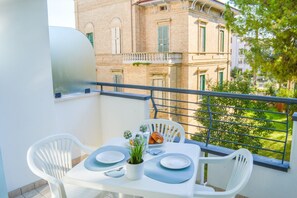 A balcony with a table set for two, a potted plant, and a croissant.