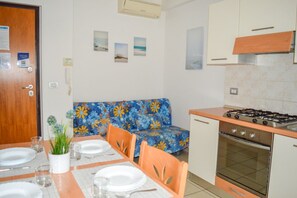 A compact kitchen with a gas stove, oven, and a dining area with a table set for two.