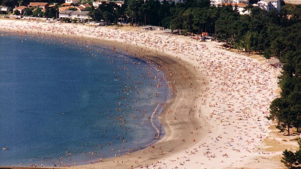 Une plage avec un pont au premier plan.