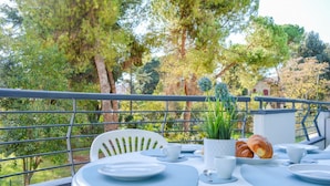 A balcony with a table set for breakfast, including croissants and coffee cups, overlooking a lush garden and a house. - Holiday Rendez Vous 40 - Third floor apartment with side sea view (Pineto)