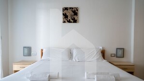 A neatly made bed with white linens and two pillows, flanked by two bedside tables with lamps and framed pictures. - Holiday Rendez Vous 13 - Ground apartment with balcony and side sea view (Pineto)