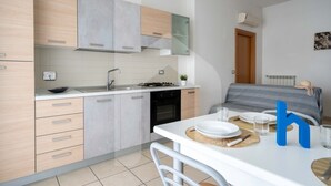 A modern kitchen with light wood cabinets, a white countertop, and a dining area with a table set for two. - Holiday Rendez Vous 13 - Ground apartment with balcony and side sea view (Pineto)