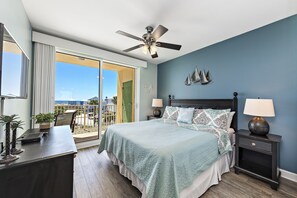 Une chambre à coucher comprenant un lit, un bureau, une chaise, une table de chevet et un ventilateur de plafond.