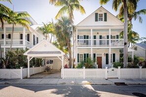 Stunning colonial-style residence with a central entrance, flanked by two balconies, and a charming picket fence.