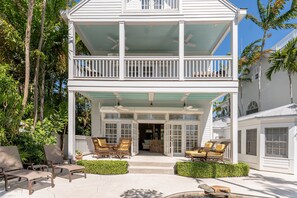 A two-story house with a covered porch, outdoor furniture, and a view of the surrounding greenery.