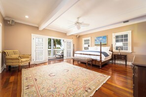 A bedroom with a large bed, a ceiling fan, a window with blinds, a chair, and a view of the outdoors. - Key West Oasis - Truman Annex Estate (Key West)