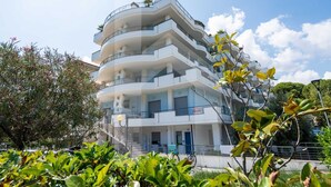 Een meerhoog gebouw met balkons, een trap en een bord dat aangeeft dat het een hotel is.