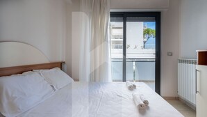 Ein Hotelzimmer mit Bett, einem Fenster mit Vorhängen, Blick auf einen Balkon und einer Heizung.