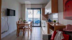 Eine moderne Küche mit Essbereich, einem an der Wand befestigten Fernseher und einer Glastür zu einem Außenbereich.