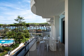 A balcony with a pool view, white chairs, and a table. - Holiday Rendez Vous 24 - First-floor apartment with a side view of the ocean (Pineto)