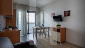 Een moderne keuken met een eethoek, een aan de muur bevestigde televisie en een klein plantje op het aanrecht.
