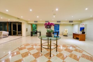A reception area with a checkered floor, a glass table with a plant, a reception desk, and a blue banner.