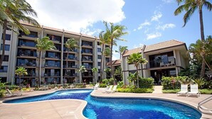 Un albergo con piscina, palme e un edificio con numerosi balconi.