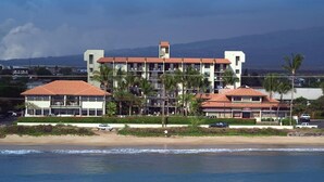 Un hotel sulla spiaggia con numerosi balconi, vista mare e montagne sullo sfondo.