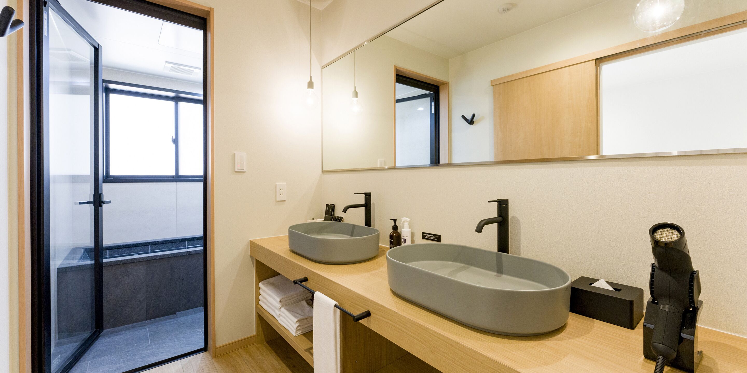 A modern bathroom with two sinks, a mirror, and a hairdryer.