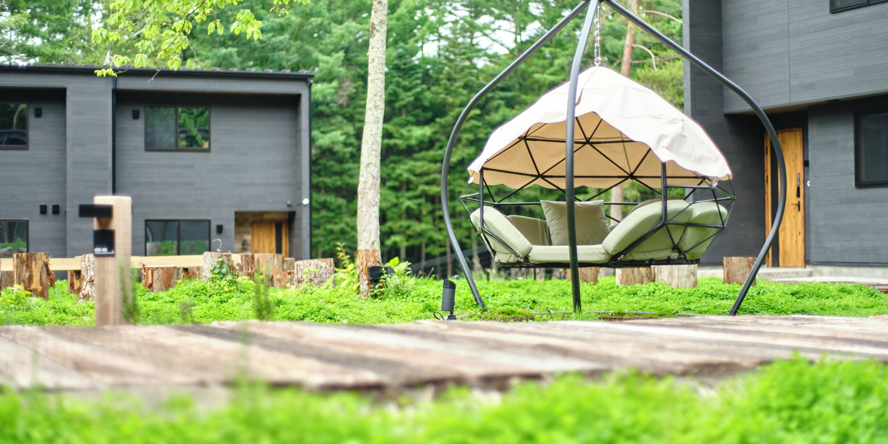 A modern outdoor seating area with a hanging chair and a wooden deck.