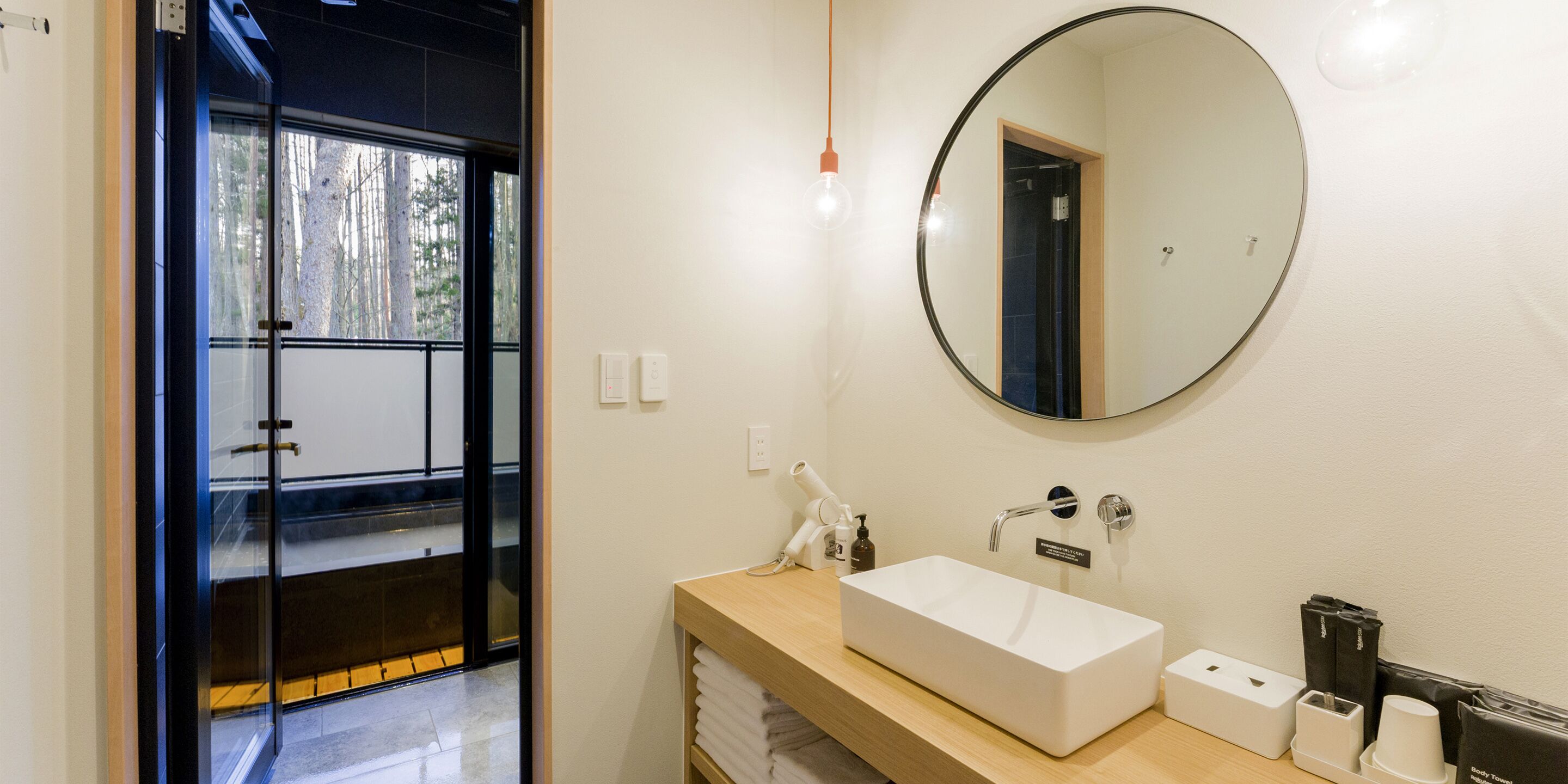 Un baño moderno con un espejo grande, un lavabo blanco y un mueble de tocador de madera.