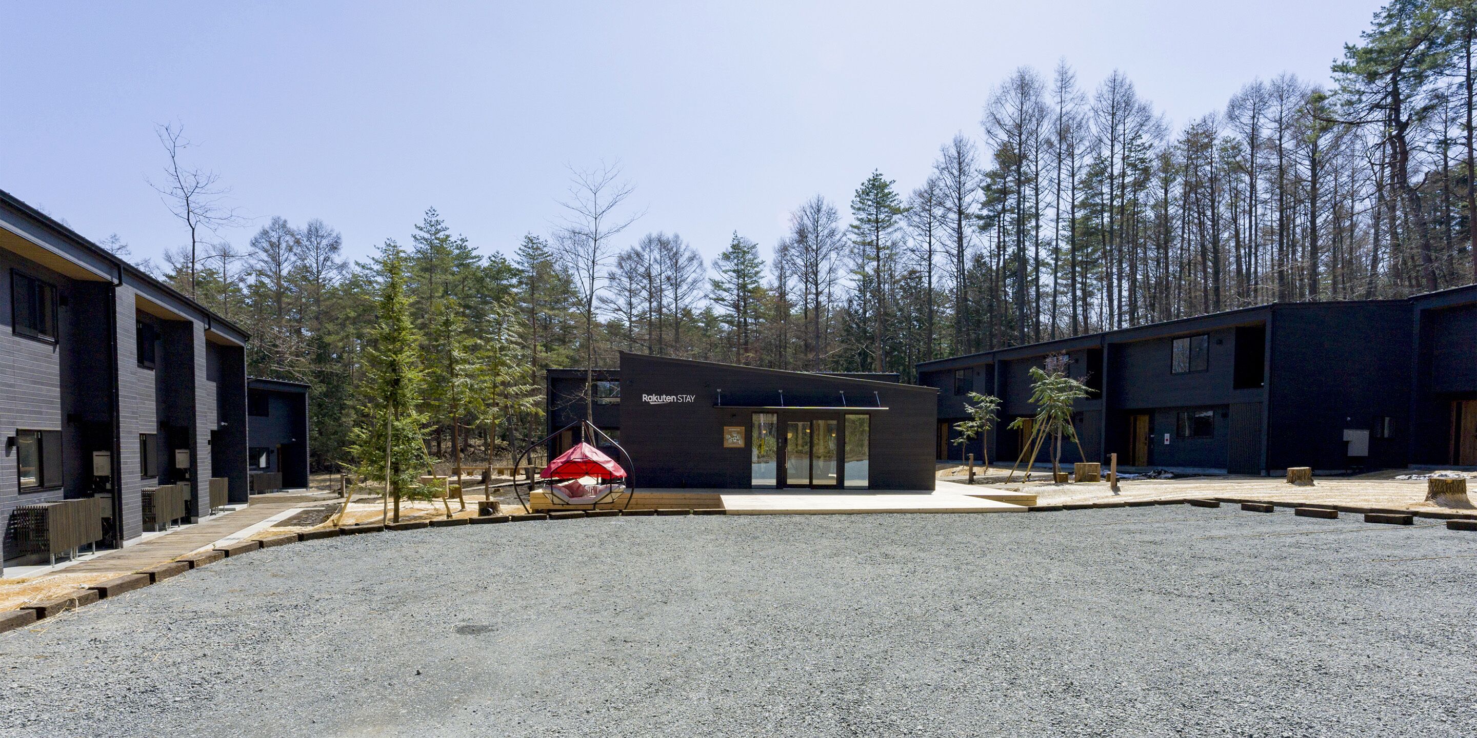 A modern building with a gravel courtyard, surrounded by trees.