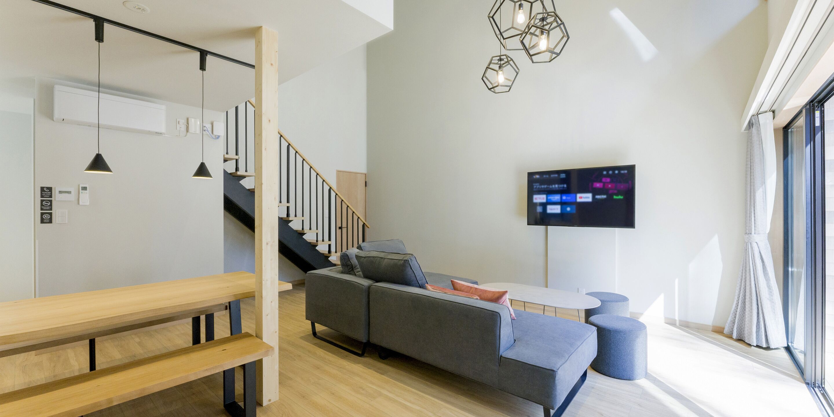 A modern living room with a sofa, a coffee table, and a TV mounted on the wall.