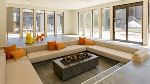 A spacious lobby with a large seating area, a fire feature, and large windows offering views of the outdoors. - Rakuten STAY VILLA FujiKawaguchiko Forest (Fujikawaguchiko)