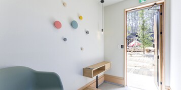 Un interior moderno con un banco de madera, una repisa montada en la pared y una puerta que da al exterior.