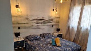 Un dormitorio con cama, mesitas de noche, un mural en la pared y una ventana con cortinas.